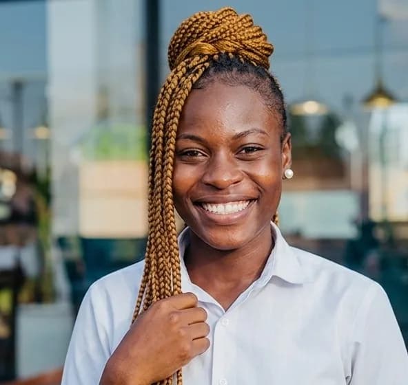 Une coiffeuse du salon, souriante, avec de longues tresses dorées